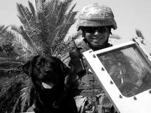 Sam Olinger, U.S. Army 4th Infantry Division, pictured in Baghdad with his Puppies Behind Bars-raised black lab, Larry.
