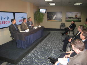 David Holland (right), Senior Vice President and Treasurer, Cisco Systems, addresses the media and representatives of AT & T and Cisco Systems as Matt Moore of AT & T (left) and Kevin Uhlich (center) of the Kansas City Royals look on.