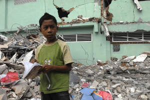 Andi, 14 years, looks at a book he found in the debris of a damaged classroom in Padang, Indonesia. 