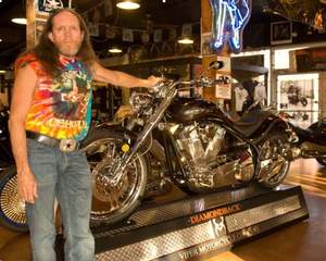 A photo of Rick Fairless in front of the Viper Diamondback showcased on its branded display at Fairless's motorcycle store  