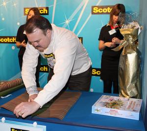 John Rutherford of Cincinnati, Ohio, 'wrapped up' a $2,500 cash prize as the first-runner up in the Scotch Brand Most Gifted Wrapper Contest on Friday, December 4 in a national gift-wrapping contest held at Rockefeller Center. Rutherford shows off his technique as he wraps a jigsaw puzzle in Round 1 of the contest.