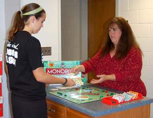 Monopoly Money Makes it Real contest winner, Julie Nusbaum, plays Monopoly with a local high school student. 