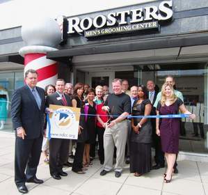 Daryl Hendrix, owner of Roosters Men's Grooming Center in Preston Center, cuts the ribbon for the store's opening, assisted by representatives of the North Dallas Chamber and Roosters' staff.