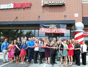 At center, Bob Jackson, owner of Roosters Men's Grooming Center in Murfreesboro, receives assistance during the store's ribbon cutting from family, staff, community leaders and members of the Rutherford County Chamber of Commerce.