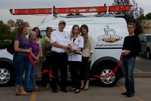 Neil and Elena Boyer, at center, of Dryer Vent Wizard, cut the offical ribbon for their new franchise, with assistance from friends and representatives of the Aurora Chamber of Commerce
