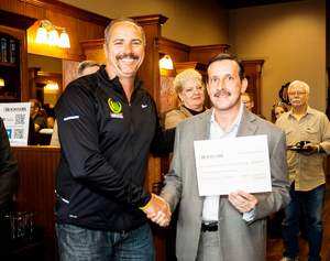 Chris Brewer of the LIVESTRONG Foundation, at left, accepts a check for $500 from Mike McHenry, owner of the new Roosters MGC in Cedar Park.