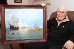 Ed Lore displays one of his own paintings that hangs in his Oakwood Common apartment.