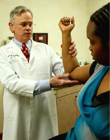 Board certified plastic surgeon Dr. David Reath examines arm lift patient Natalie Robinson. New statistics released by the American Society of Plastic Surgeons (ASPS) show arm lifts in women have skyrocketed more than 4,000 percent since 2000.  Courtesy: American Society of Plastic Surgeons