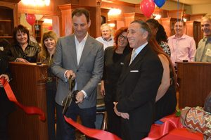 Michael Stajer, owner of Roosters Men's Grooming Center in San Mateo, cuts the ribbon for the store's opening with assistance from Mayor Robert Ross