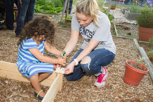 A young girl helps an IMOne volunteer plant new growth for her neighbors.