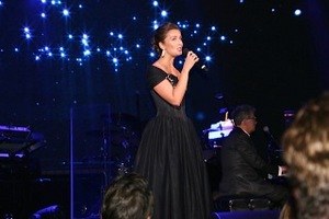 Carly Paoli performing on stage at DFF Miracle Gala accompanied by David Foster on piano
