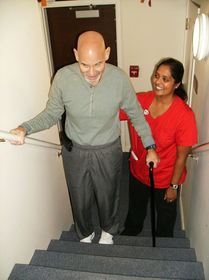 Physical Therapy Supervisor Dr. Susha Thomas helps John Goch as he learns to walk up stairs following hip replacement surgery