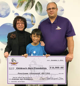 Scott Thomas, director of operations for Dryer Vent Wizard, presents the company's donation to Carol Horvitz, executive director of Children's Burn Foundation and child burn survivor Regimar Pablo, age 11.