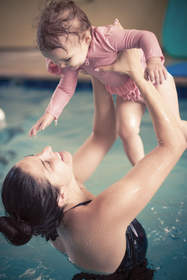 Woman holding baby in pool.