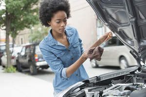 Woman checking engine oil in car