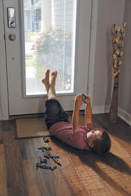 Boy playing with toy while lying on the floor next to a door.