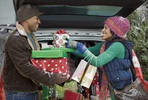 Man and woman unloading gifts from car.