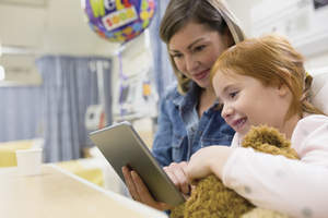 Woman and young girl looking at a computer tablet.