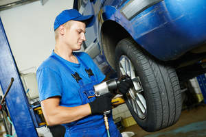 Technician installing tires on car.