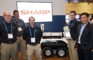 The Sharp team poses with its home surveillance robot and the STOBA(R) - inside battery module at ASIS 2016 in Orlando.