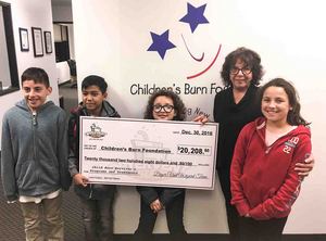 Carol Horvitz, executive director of the Children's Burn Foundation, displays the donation from Dryer Vent Wizard, with assistance from children who have survived burns and received help from the non-profit.