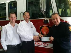 Fire Chief James Wall of King Fire and Emergency Services in King City, Ontario accepts the DVW grant from franchisee Tyler Johnson, at center, and DVW technician Leighton Johnson of Dryer Vent Wizard of York, Ontario.