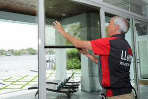 LLumar professionally-trained installer applying the window film, showcasing the skill and care a professionally-trained installer uses in the installation process.
